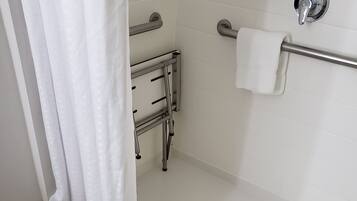 A modern bathroom with a shower, grab bars, a towel rack, and a toilet.