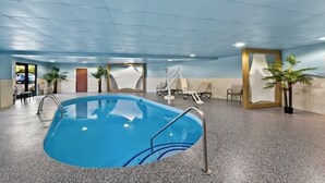 An indoor swimming pool with a blue tiled floor, a clear pool, and a few lounge chairs and potted plants around. - Holiday Inn Express & Suites Raleigh NE - Medical Ctr Area by IHG (Raleigh)