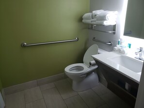 Bathroom features a white sink, mirror, and toilet, with a grab bar for added safety.