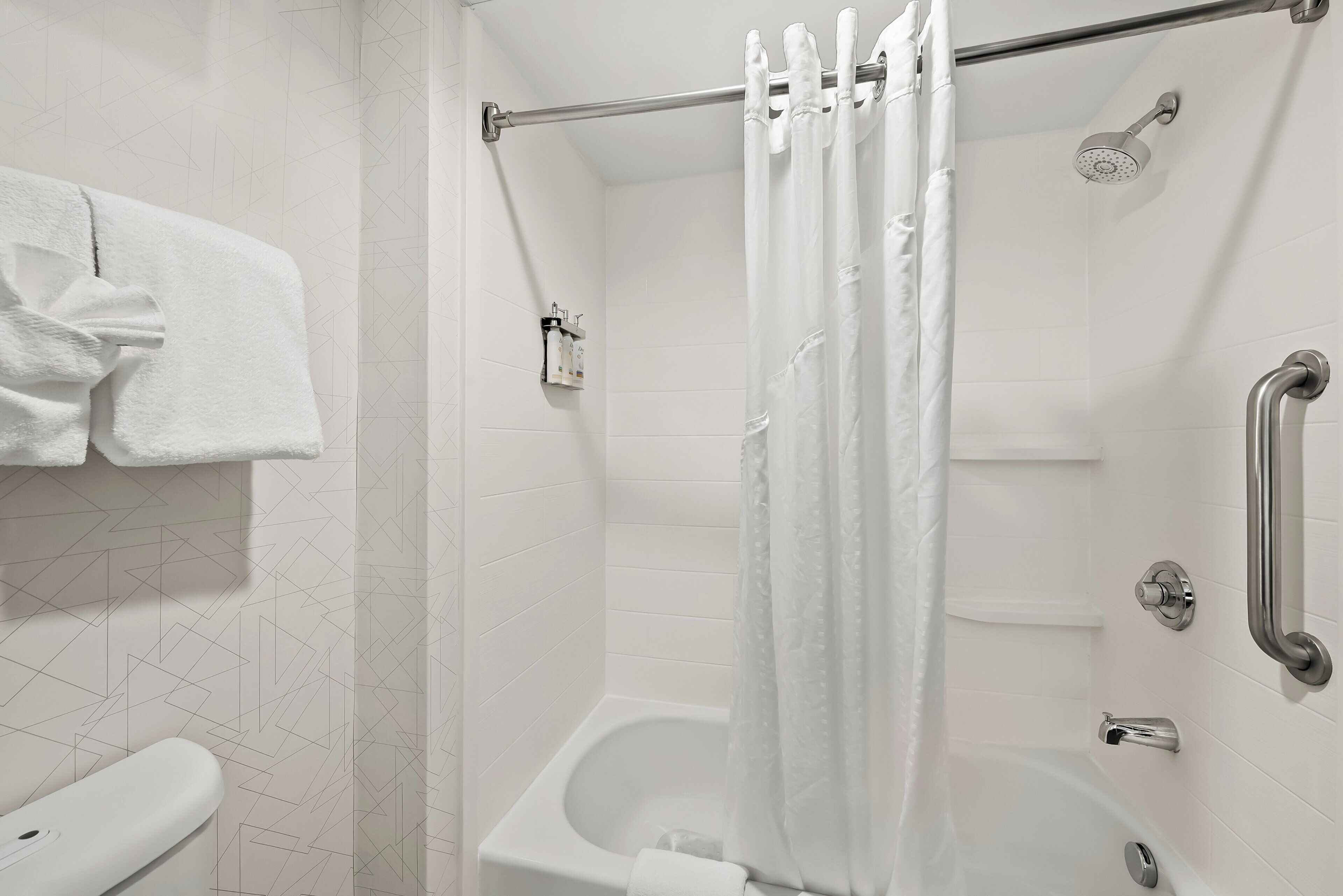 Un baño con ducha, inodoro y un perchero para toallas.