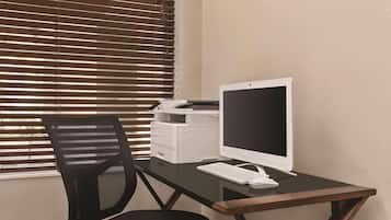 A desk with a desktop computer, a printer, and a black office chair.