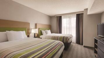 A hotel room with two beds, a television, and a window with curtains.