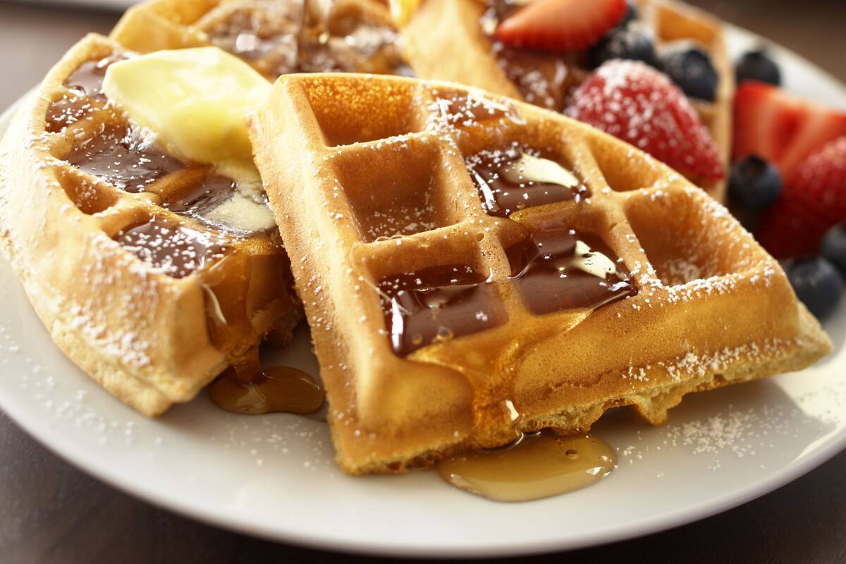 A plate with waffles topped with syrup, butter, and fresh berries.