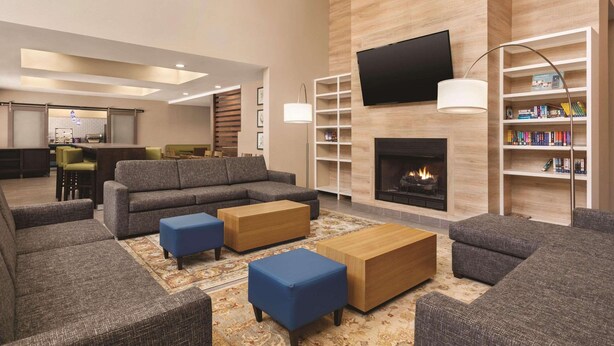 A modern living room with a fireplace, a flat-screen TV, and a bookshelf. - Country Inn & Suites by Radisson, Beaufort West, SC (Beaufort)