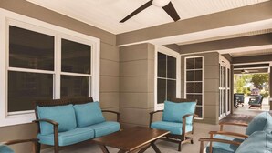 An outdoor patio with a brown table, blue sofas, and wooden chairs. - Country Inn & Suites by Radisson, Beaufort West, SC (Beaufort)