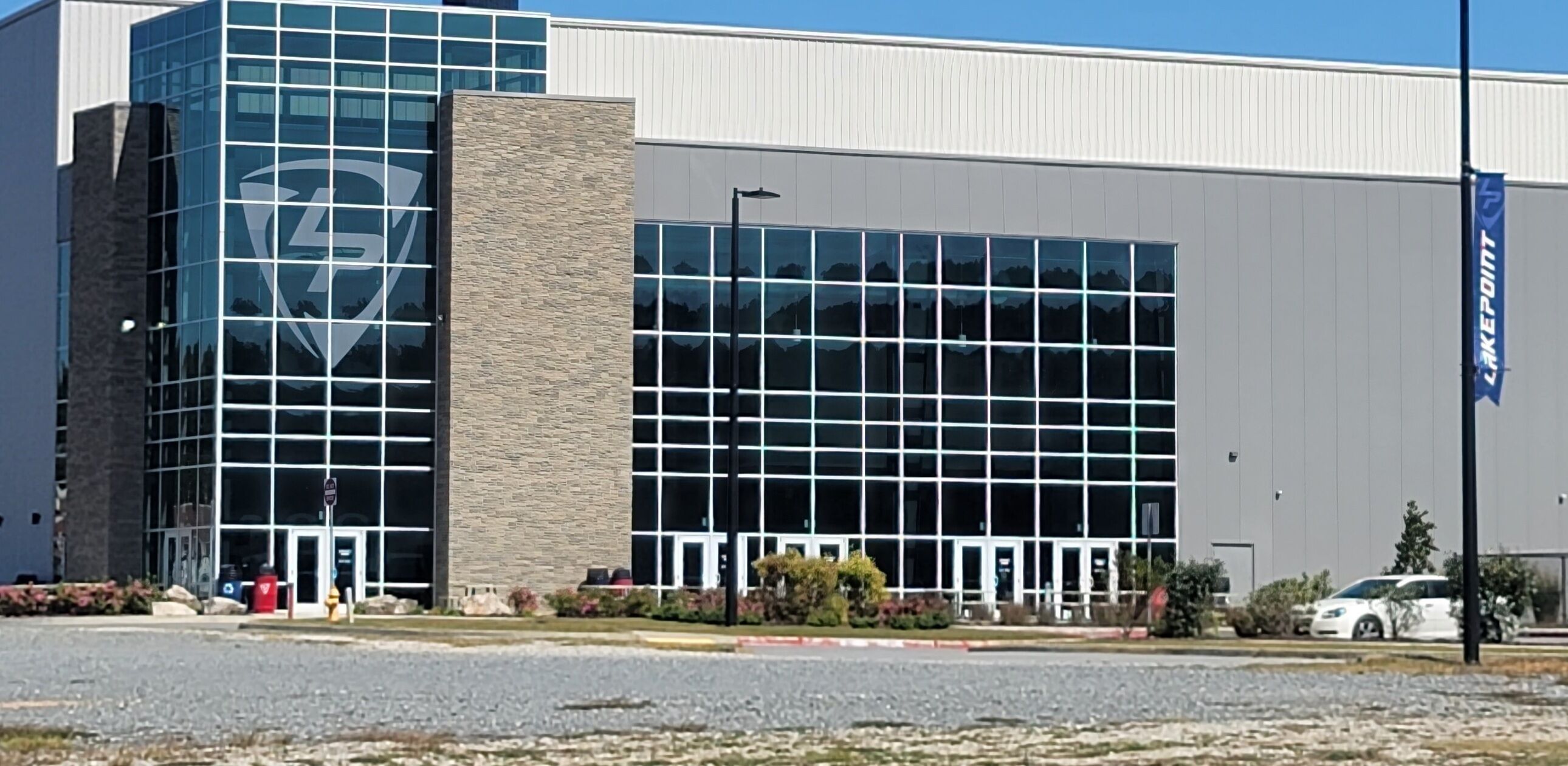 A modern building with a glass facade and a stone base, featuring a large logo on the glass.