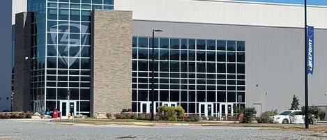 A modern building with a glass facade and a stone base, featuring a large logo on the glass.