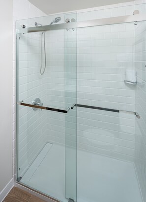 A glass-enclosed shower with a handheld showerhead and a towel rack. - Four Points by Sheraton Chicago Schaumburg (Schaumburg)