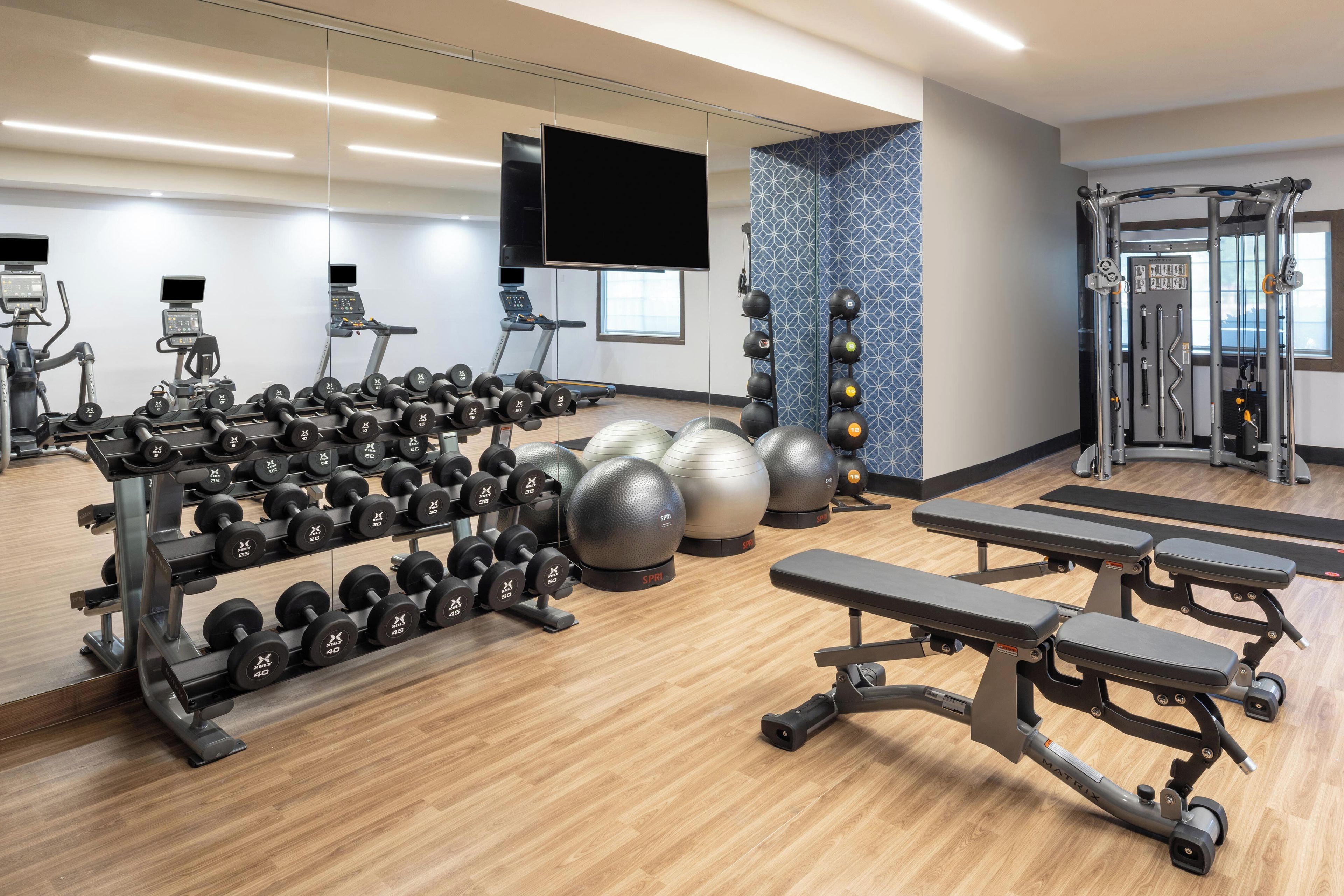 A gym with various exercise equipment, including dumbbells, medicine balls, and a treadmill.
