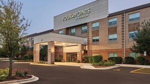 Un hotel Four Points by Sheraton con fachada de ladrillo, un acceso cubierto y un estacionamiento.