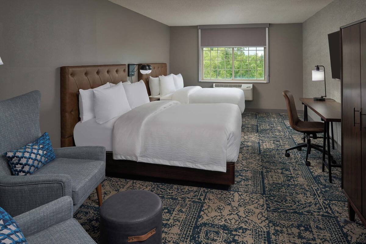 A hotel room with a large bed, a desk, a chair, and a couch.