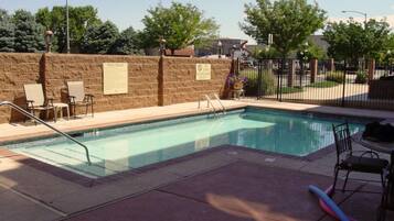 A swimming pool with lounge chairs and a 'No Lifeguard On Duty' sign.