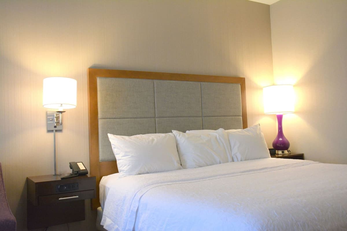 A hotel room with a bed, two bedside lamps, a nightstand, and a telephone.