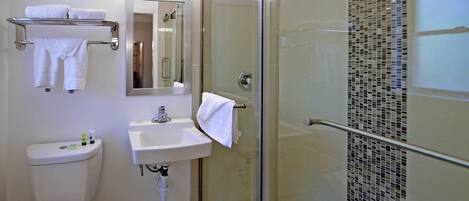 A modern bathroom with a glass-enclosed shower, a white sink, and a toilet.