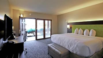 Habitación de hotel con una cama grande, un escritorio, un televisor de pantalla plana, una computadora portátil y una ventana con vistas al exterior.