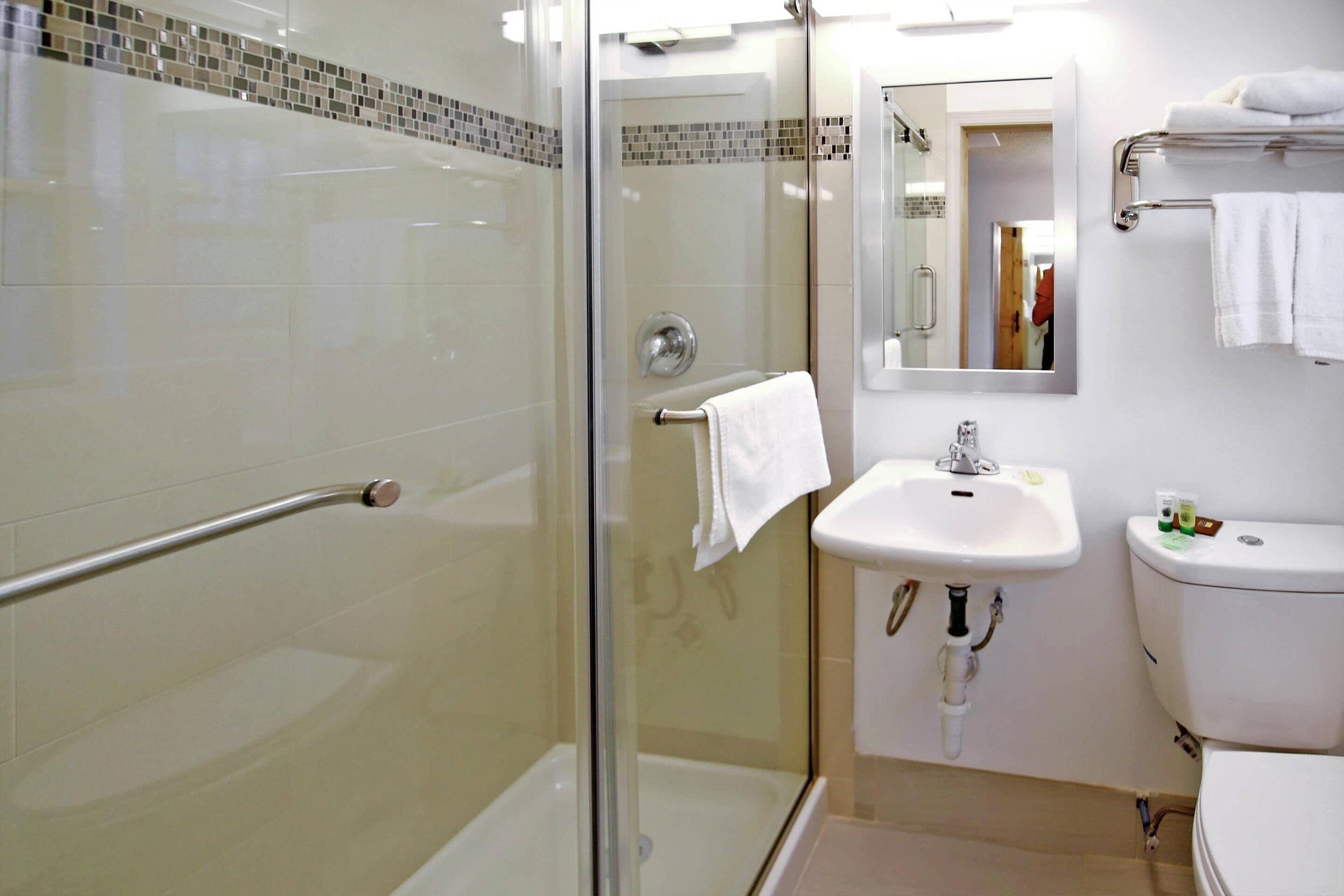 Une salle de bain moderne avec une douche à parois de verre, un lavabo blanc et des toilettes.