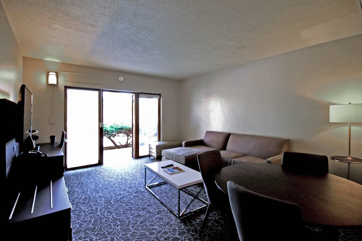 A hotel room with a sofa, a coffee table, a TV, and a lamp.