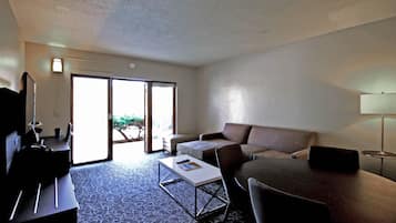 Habitación de hotel con sofá, mesa de centro, televisor y lámpara.