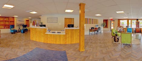 A reception area with a wooden reception desk, a computer, and seating arrangements including chairs and a sofa.
