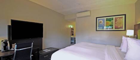 Habitación de hotel con una cama grande, un televisor de pantalla plana, un escritorio con una silla y un cuadro en la pared.