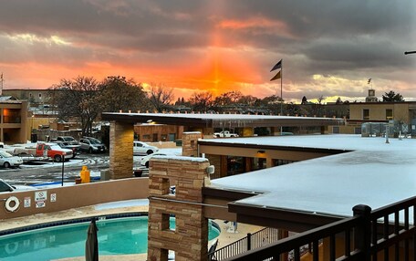A hotel with a pool, a parking lot, and a sunset view.