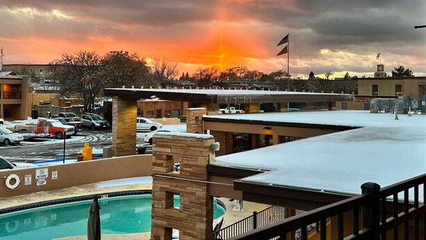 A hotel with a pool, a parking lot, and a sunset view. - El Sendero Inn, an Ascend Collection Hotel (Santa Fe)