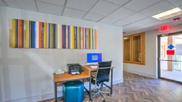 A modern office space with a desk, computer, and a blue trash bin.