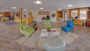 A spacious lobby with a reception desk, multiple seating areas, and large windows offering views of the outside.