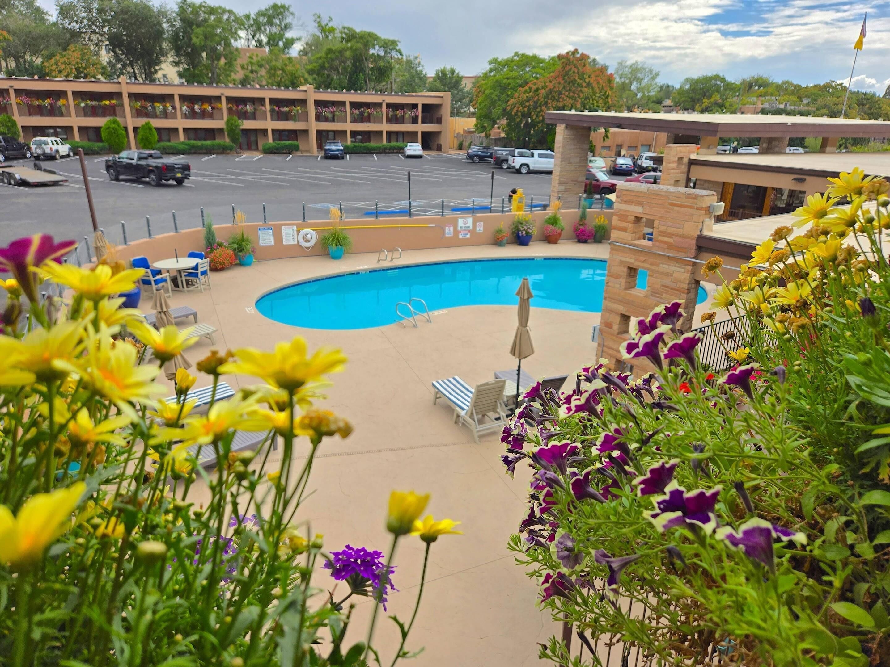 Un hotel con piscina, zona de estar al aire libre y aparcamiento.
