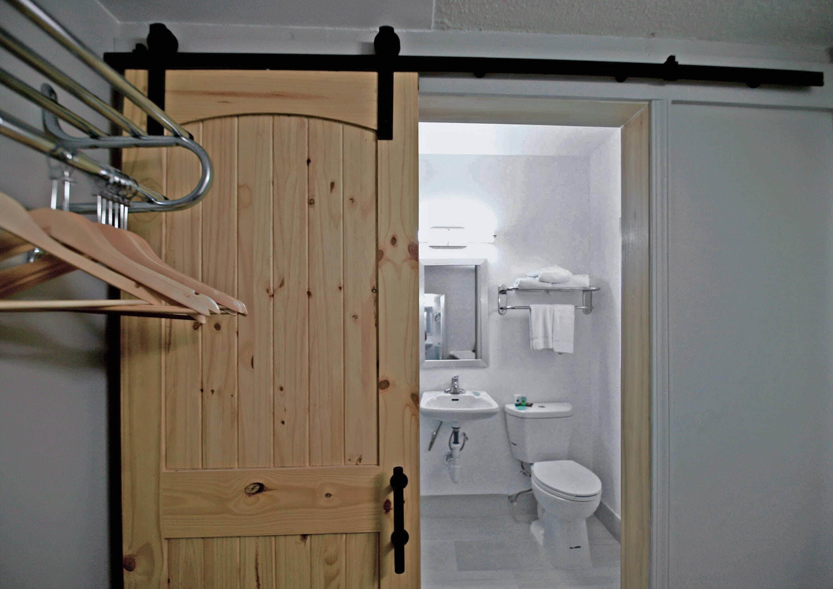 Eine Holztür mit Handtuchhalter und einem Schiebe-Stalltür-Mechanismus.