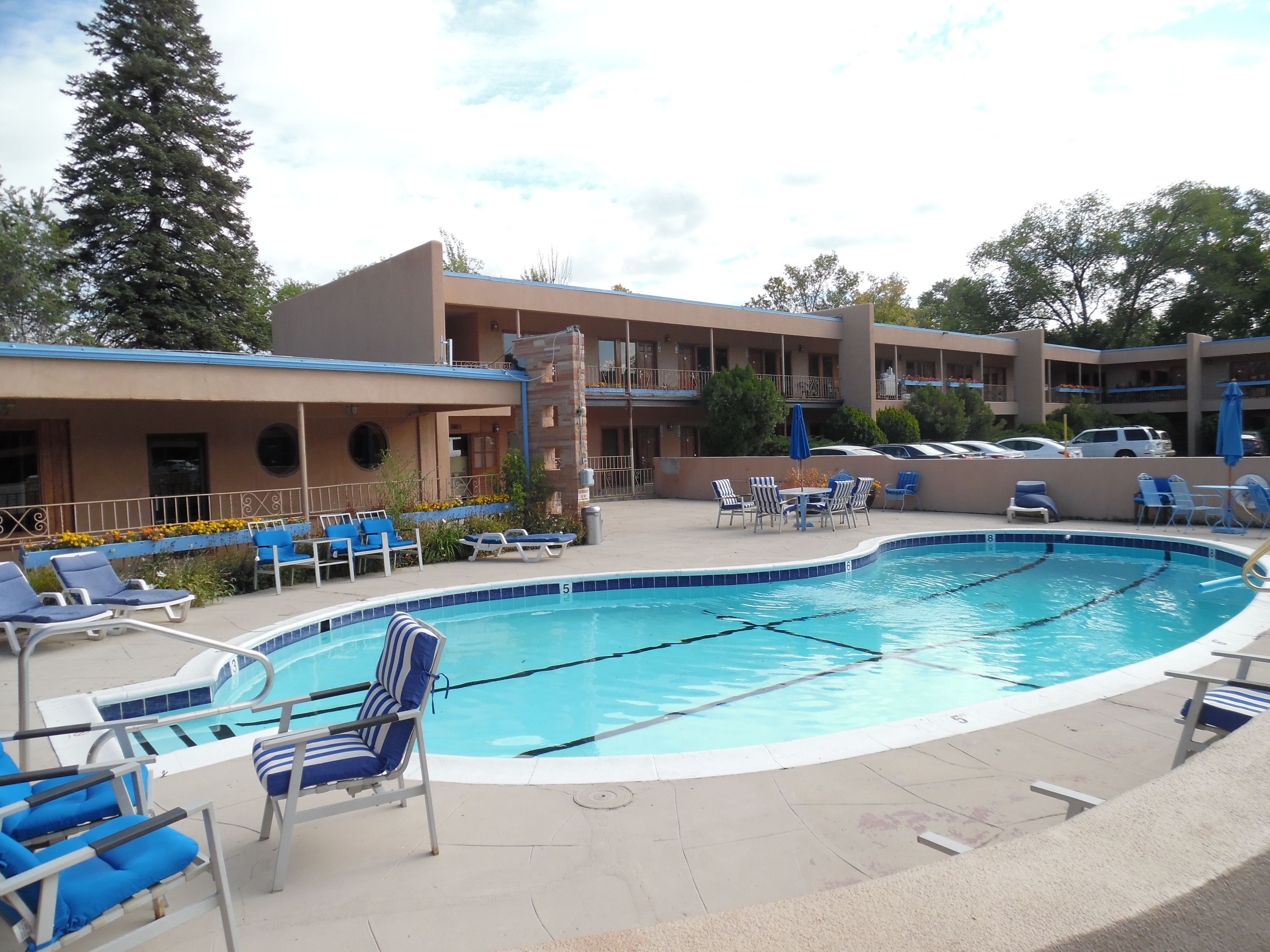 Un área de piscina con sillas de descanso, una piscina y un edificio con varios balcones.