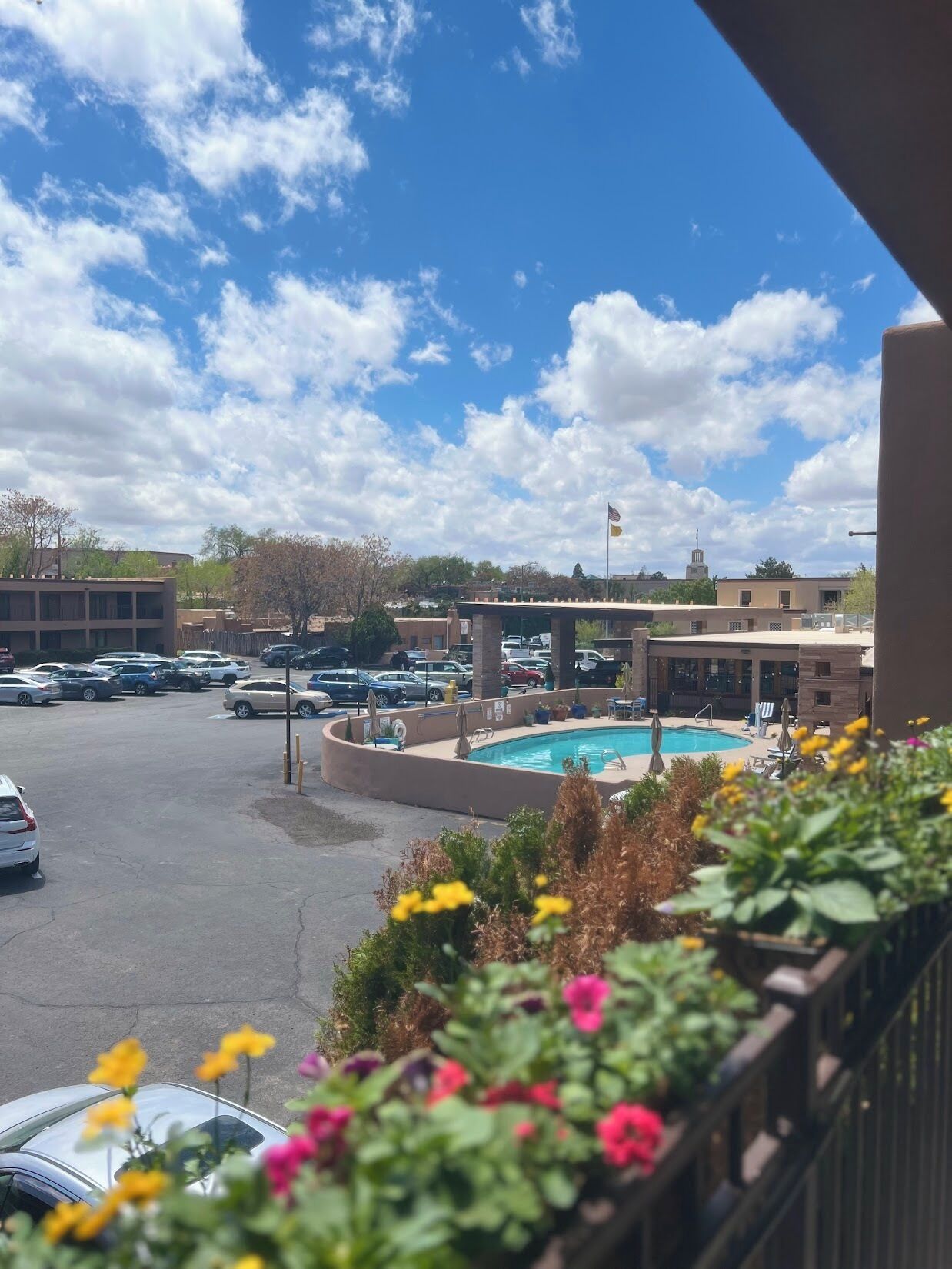 A hotel with a swimming pool, parking lot, and a view of the surrounding area.