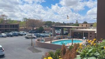 A hotel with a swimming pool, parking lot, and a view of the surrounding area.