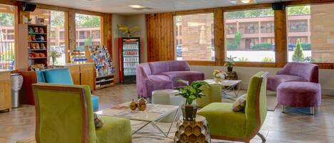A cozy lobby with purple and green chairs, a coffee table, and a vending machine.