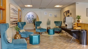 A modern interior with a reception desk, several blue armchairs, a coffee machine, and a large abstract painting on the wall. - El Sendero Inn, an Ascend Collection Hotel (Santa Fe)