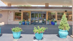 A building entrance with a glass door, potted plants, and a stone facade. - El Sendero Inn, an Ascend Collection Hotel (Santa Fe)