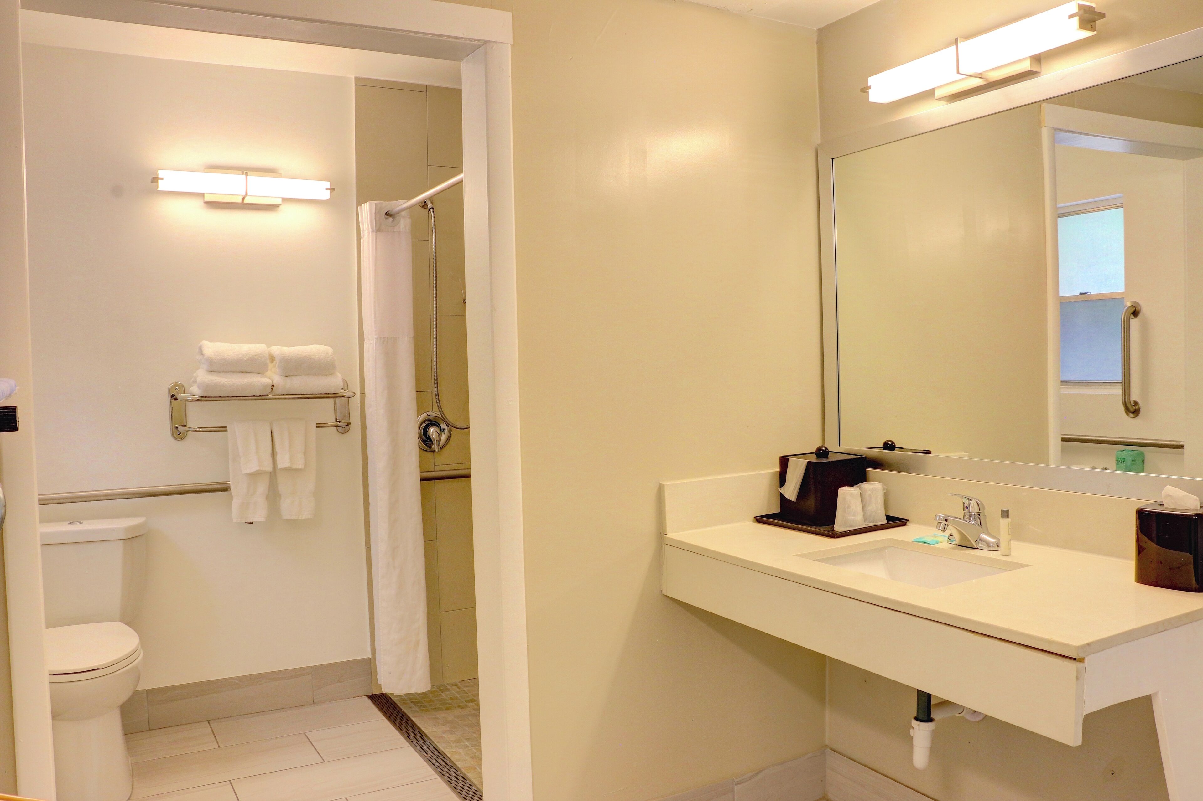 A bathroom with a toilet, a sink with a mirror, and a towel rack with towels.