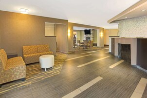 Un vestíbulo de hotel con sofá, reposapiés y chimenea.