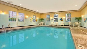 Una piscina interior con agua cristalina, rodeada de sillones de descanso y mesas.