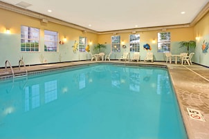 Una piscina interior con agua cristalina, rodeada de sillones de descanso y mesas.