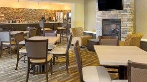 Un vestíbulo de hotel con área de bar, asientos y chimenea.