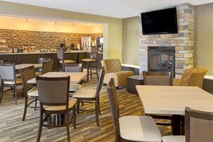 Un vestíbulo de hotel con área de bar, asientos y chimenea.