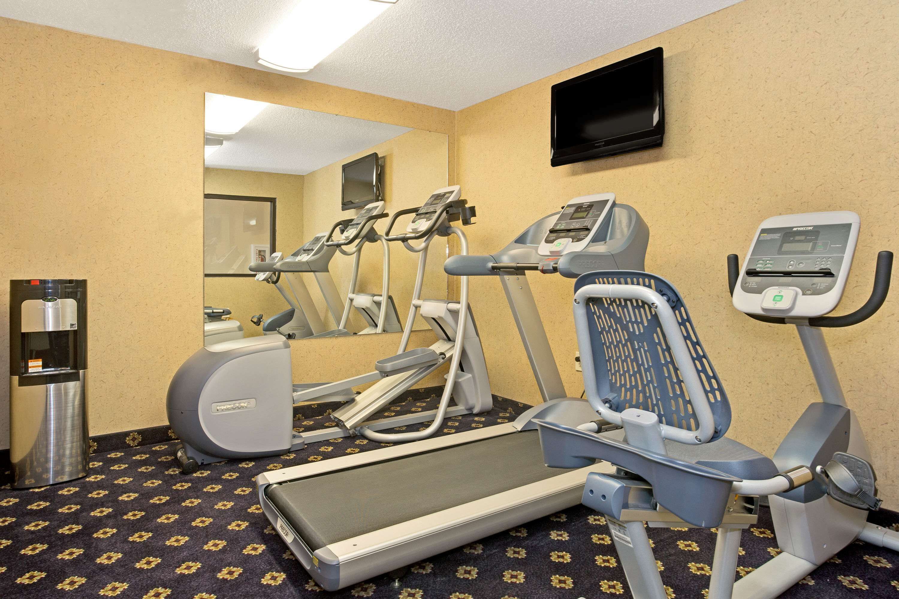 A hotel fitness room with treadmills, elliptical machines, and a water dispenser.