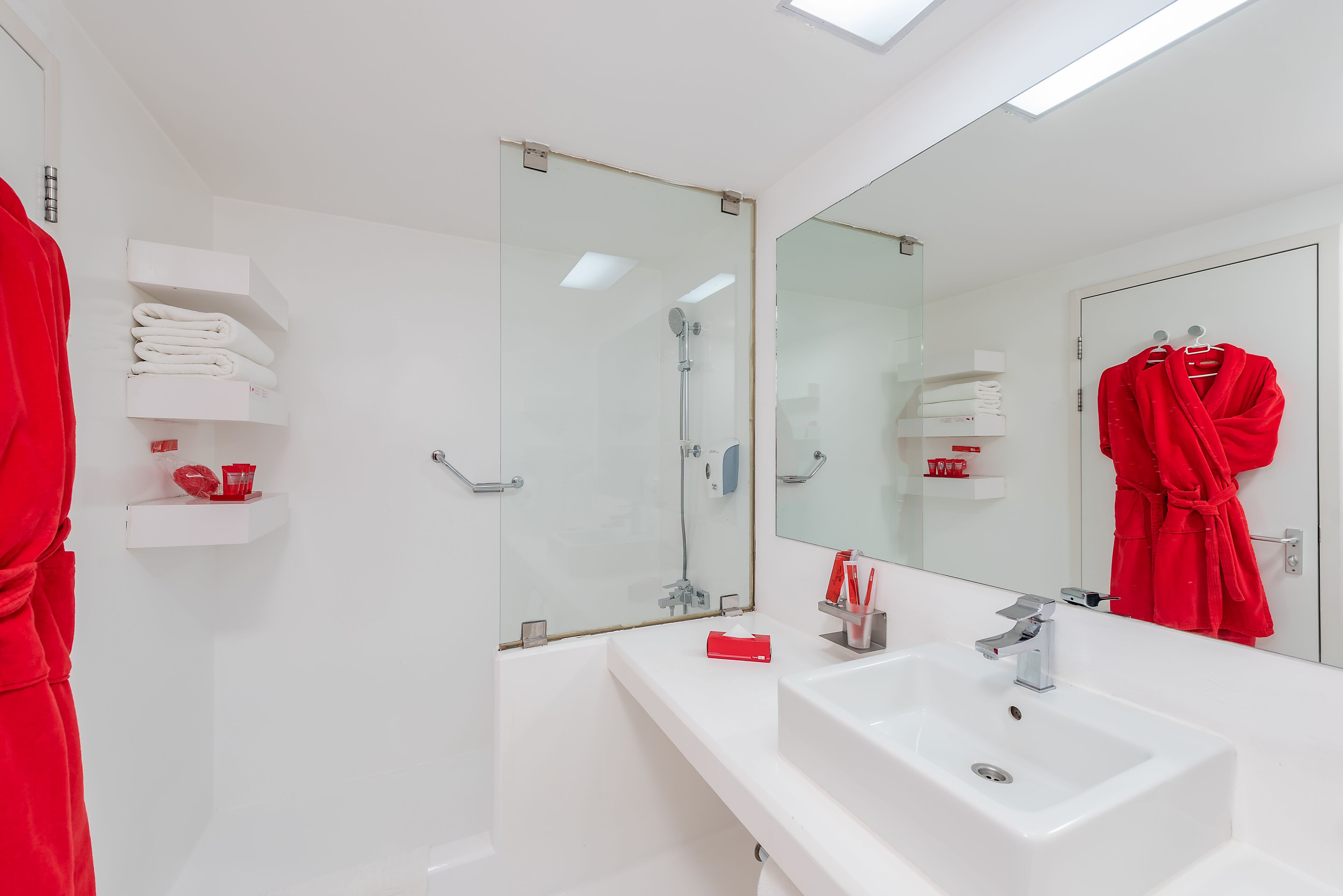 Un baño moderno con un lavabo blanco, cabina de ducha de cristal y un espejo grande.