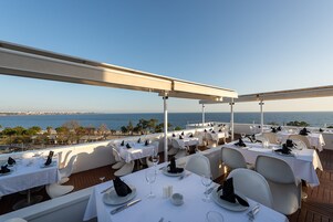 An outdoor dining area with tables set for a meal, overlooking a body of water.