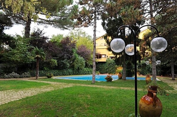 A pool surrounded by trees and a building in the background.