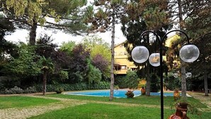 Une piscine entourée d’arbres, avec un bâtiment en arrière-plan.