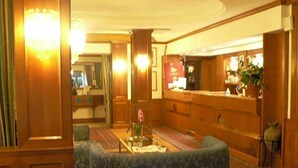 Un hall d’hôtel comprenant un comptoir d’accueil, un espace salon et un escalier.