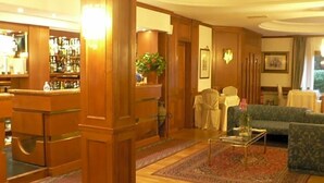 Un hall d’hôtel comprenant un bar, un espace salon et un grand pilier en bois.