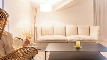 A modern living room with a sofa, a coffee table with a candle, and a person reading a book.